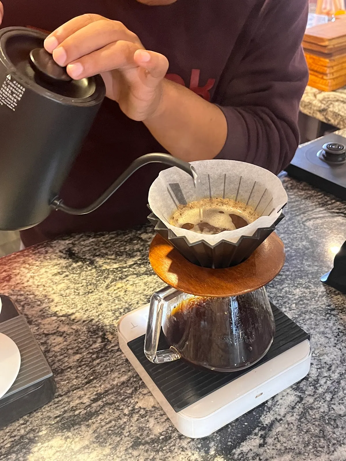 Gooseneck kettle pouring water through a paper-filter pour-over brewer