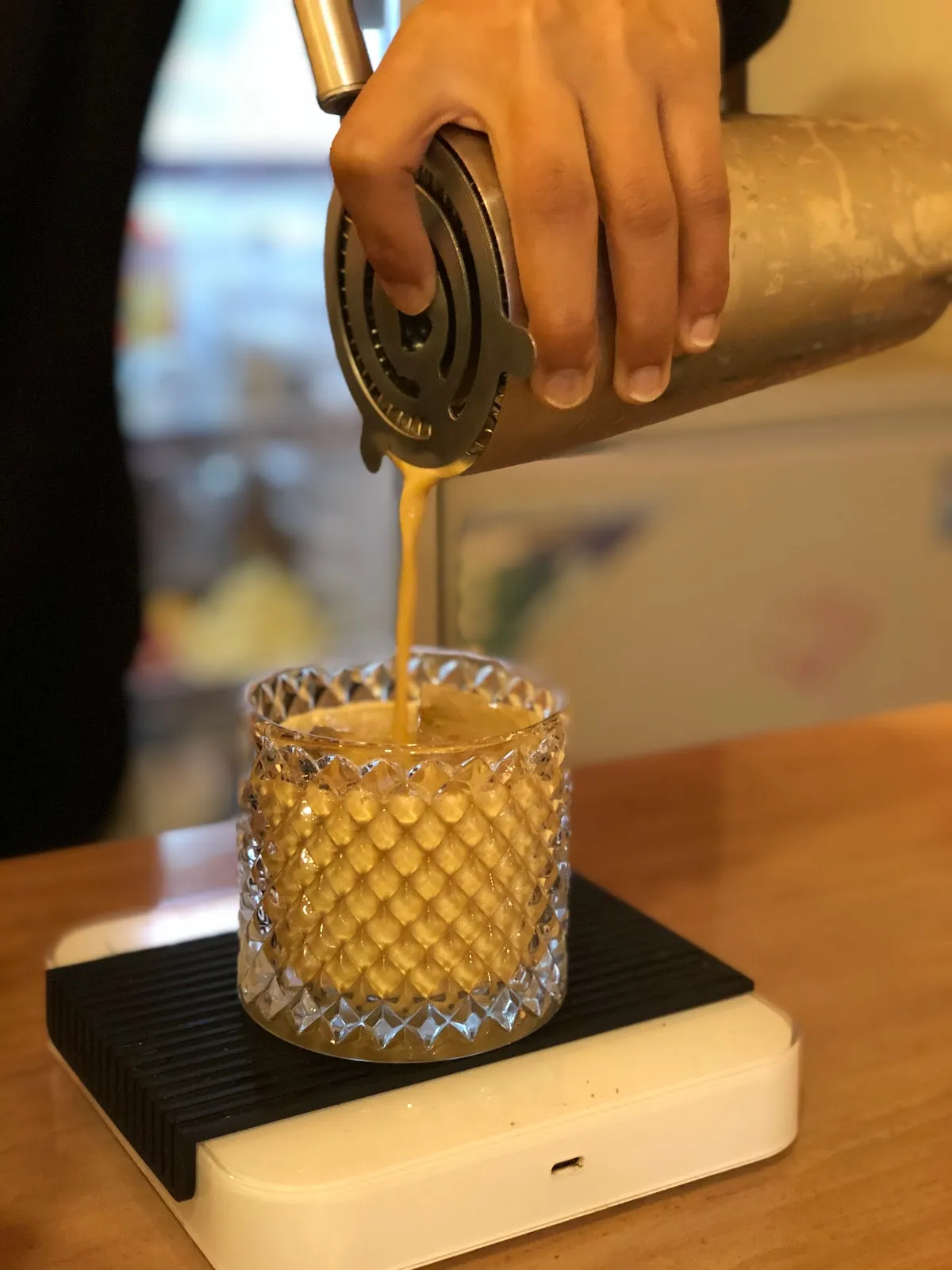 Cocktail-style shaker pouring fresh espresso into a cut-glass tumbler